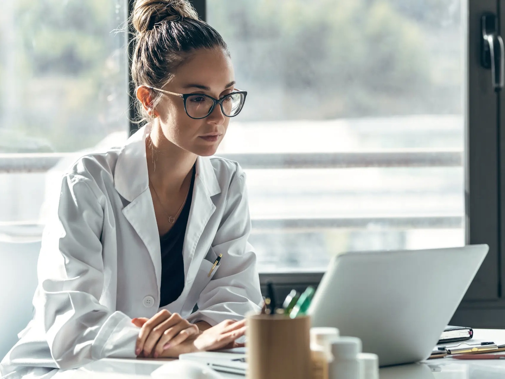 Board-certified clinician reviewing a patient case at her desk