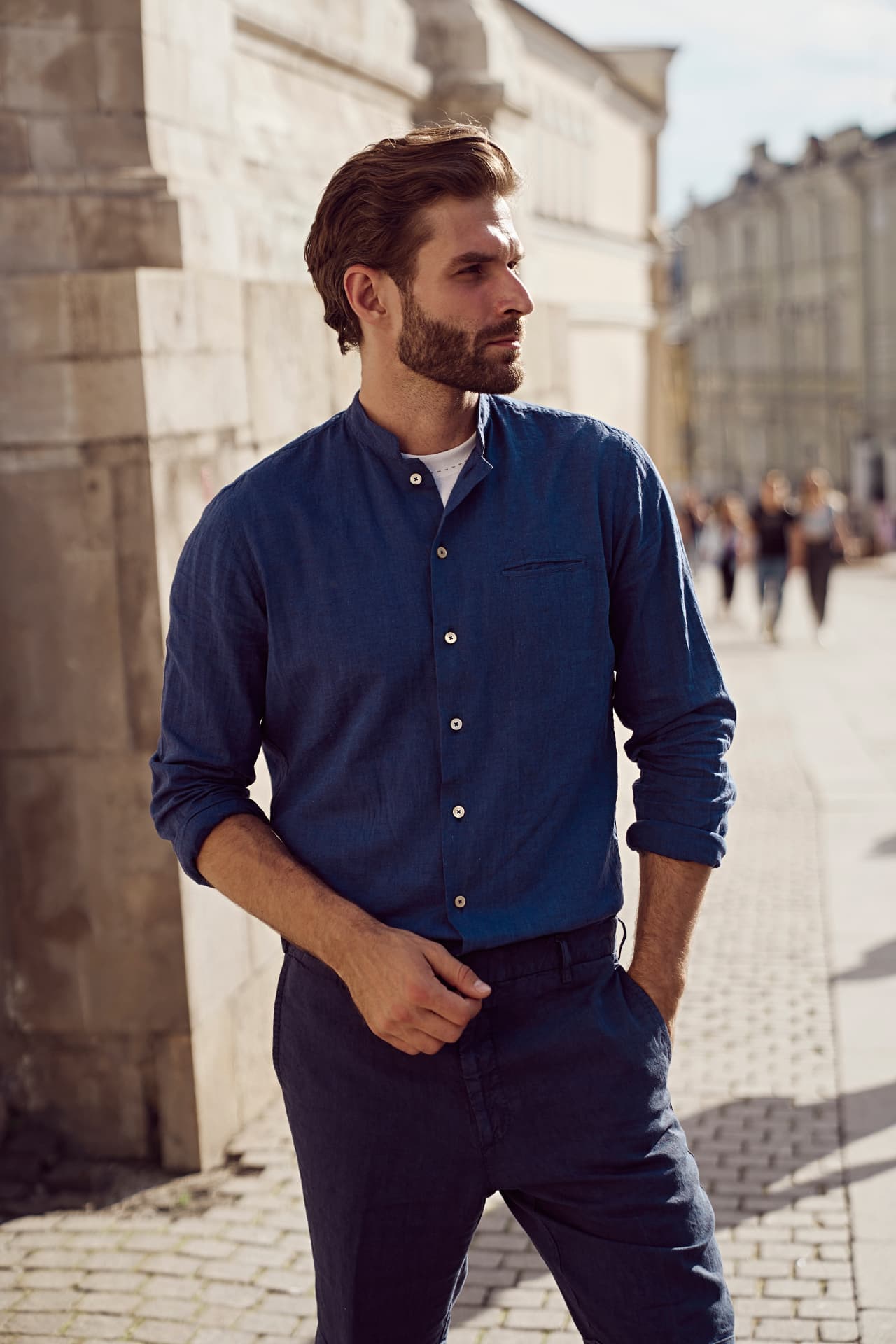 Man in a blue linen shirt on a sunlit city street