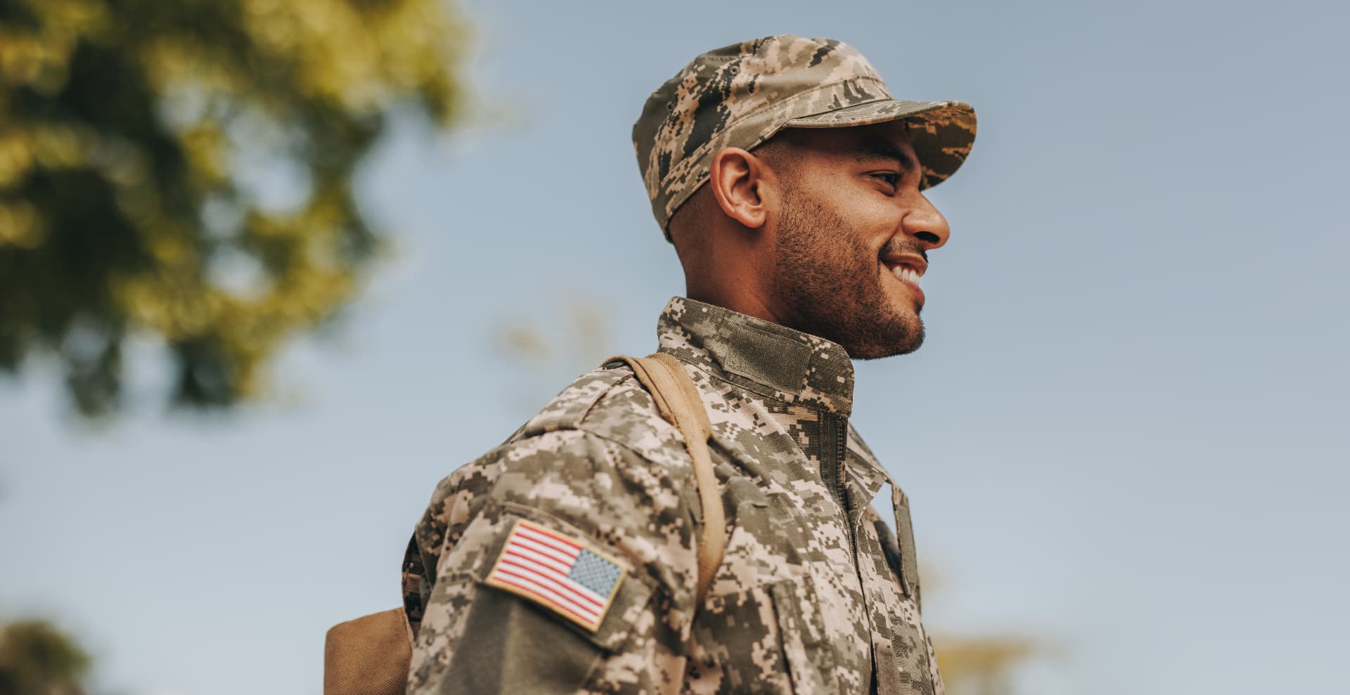 Smiling service member in camouflage uniform outdoors